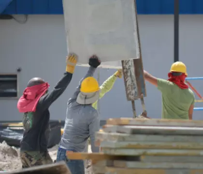 3 Männer auf der Baustelle, die Material hochheben