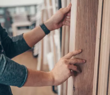Baustoffhandel, Mann der Holzplatten aus dem Regal zieht